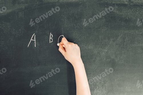 Preview: child's hand with chalk write alphabet on black chalkboard