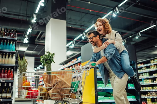 Preview: Happy couple having fun while shopping in supermarket