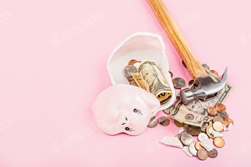 Preview: Broken piggy bank with cash money dollars bank notes and coins on pink background with copy space