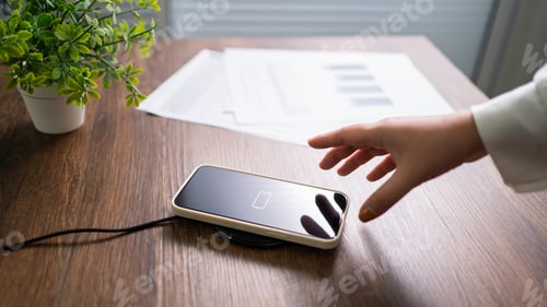 Preview: Charging mobile phone battery with wireless charging device in the table. Smartphone