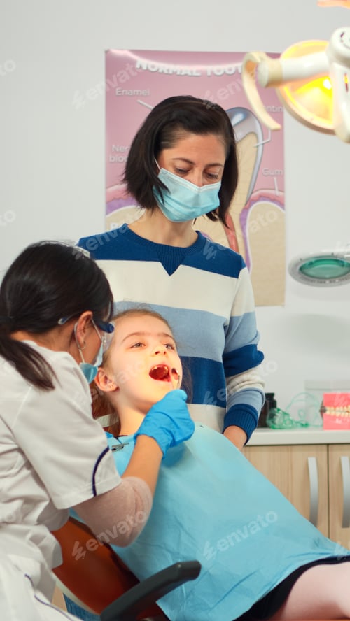 Preview: Dentist technician with gloves explaining the process to kid patient