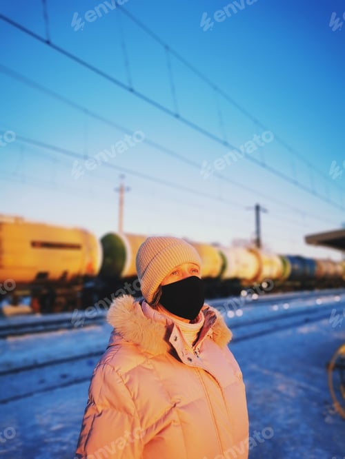 Preview: Woman wearing a mask at sunset in front of a train