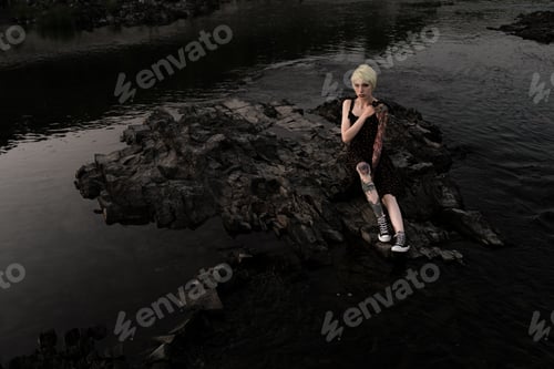Preview: a woman of non-standard appearance with tattoos on her body and a short haircut, in a dress, sitting