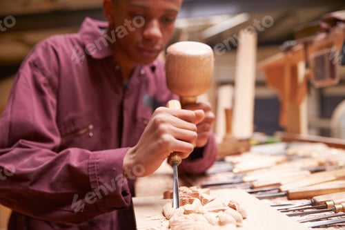 Preview: Apprentice Using Chisel To Carve Wood In Workshop