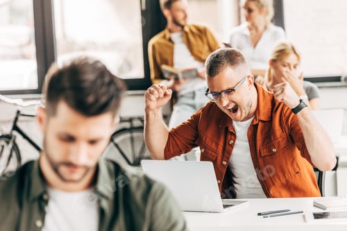 Preview: successful businessman celebrating victory while working on startup at open space office