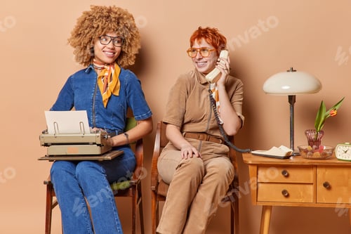 Preview: Two women dressed in old fashionable clothes diligently go about their tasks. One works on
