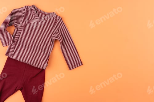 Preview: Clothes of baby girl on orange background top view