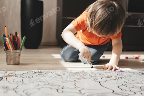 Preview: Cute little boy drawing with felt pens on floor at home. Early education concept.