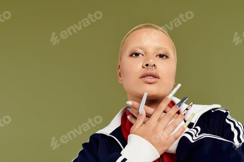 Preview: Bold expression of individuality by a young bald woman in vibrant attire against a green backdrop
