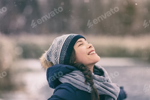 Preview: Winter woman happy enjoying snow falling on face outdoor forest nature Asian girl looking up
