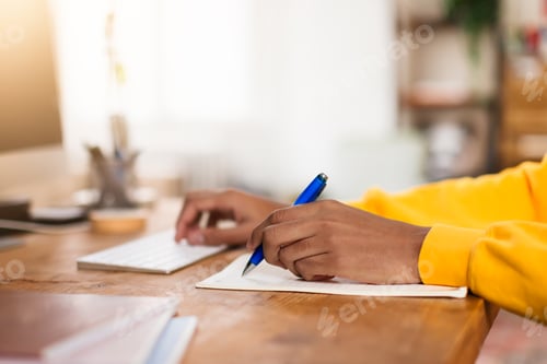 Preview: Person writing notes beside a computer