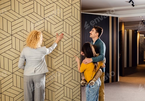 Preview: Saleswoman showing a young couple with a child the panels for decorating the interior of the home.