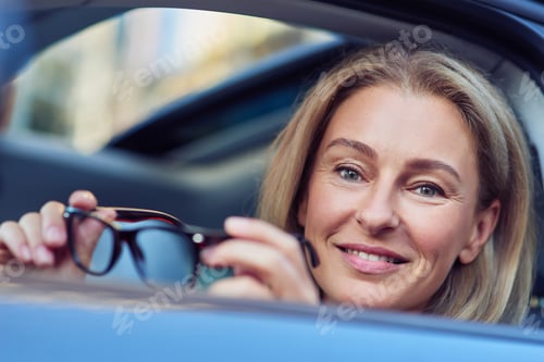 Preview: Smiling Woman Holds Eyeglasses Inside of Car