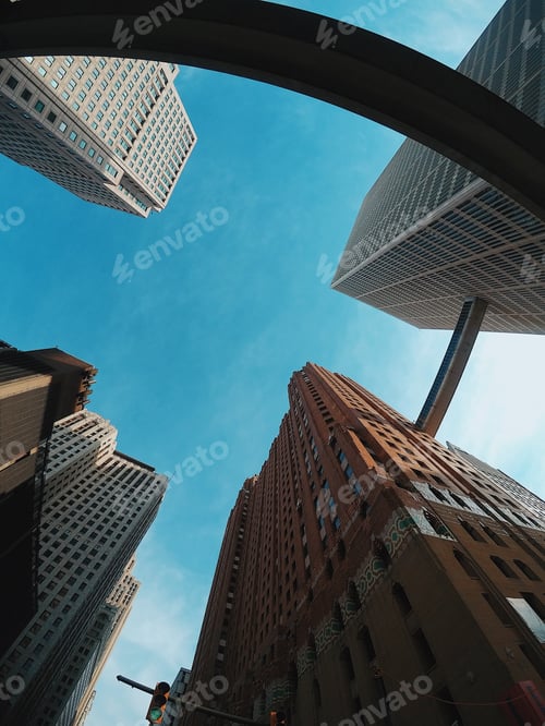 Preview: Low angle view of modern colorful skyscrapers under a blue sky and sunlight