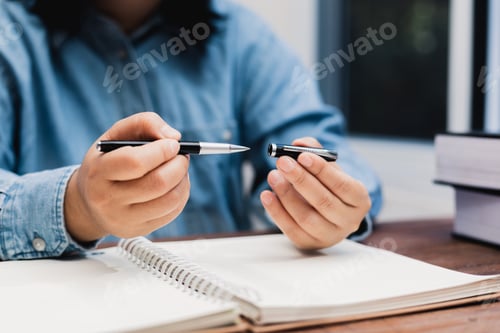Preview: woman holding a pen sitting on a desk writing