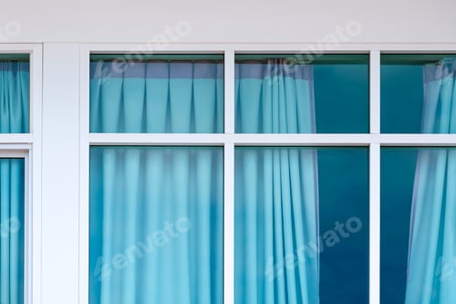 Preview: Blue curtain inside of room behind glass wall of modern white house