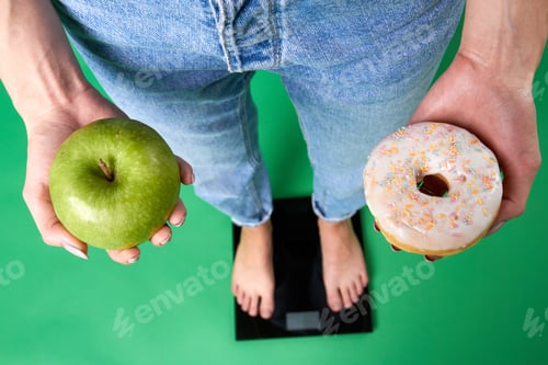 Preview: Top view of female legs in jeans standing on a scales