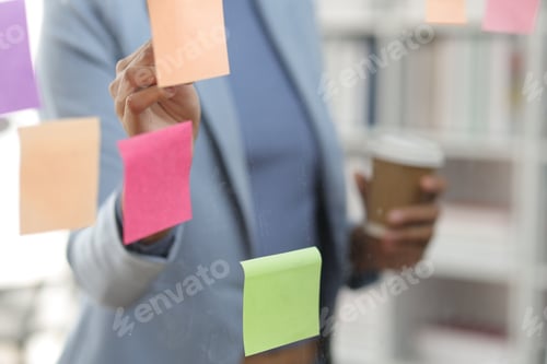 Preview: Businesswoman scheduling work strategy, planning work in the office with paper stickers on the glass