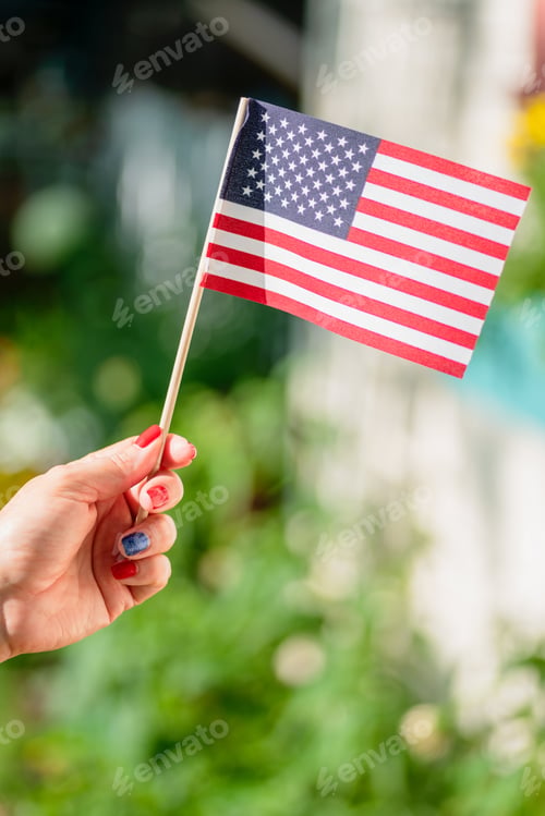 Preview: Woman’s hand waving a small American flag