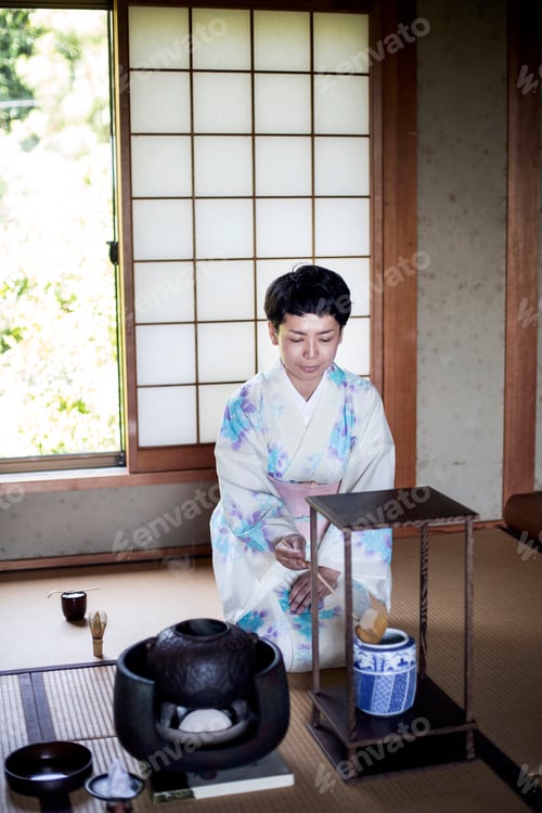 Preview: Japanese woman kneeling on tatami mat during tea ceremony.