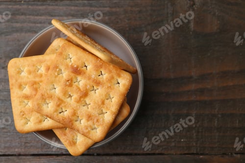 Preview: Tasty salty crackers on wooden table, top view. Space for text