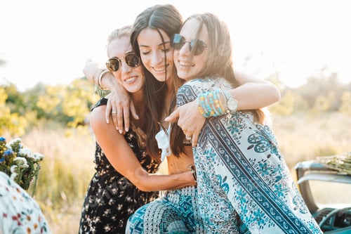 Three Young Women Embracing Outside in a Field