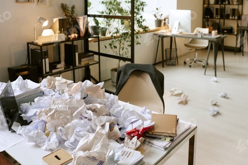 Preview: Messy Office Desk Covered with Crumpled Papers Representing Workplace Stress