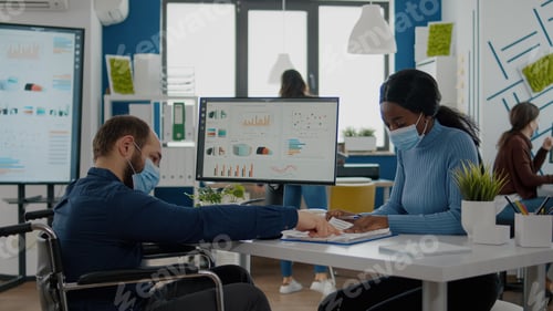 Preview: Invalid man and african employee with protective masks working together