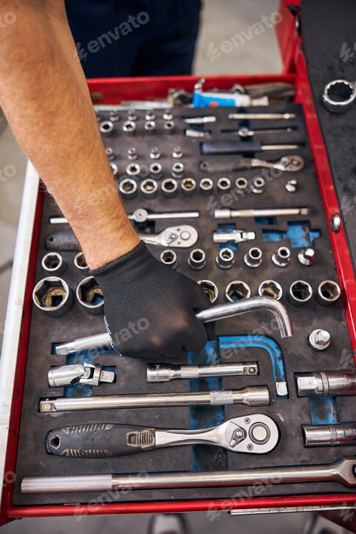 Preview: Auto mechanic grabbing curved rod wrench from vehicle tools box