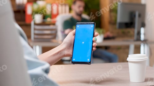 Preview: Businesswoman looking at mock up green screen chroma key modern phone with isolated display