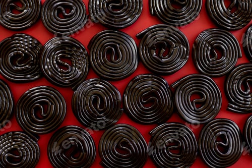 Preview: Flat lay tasty black liquorice candies on red background