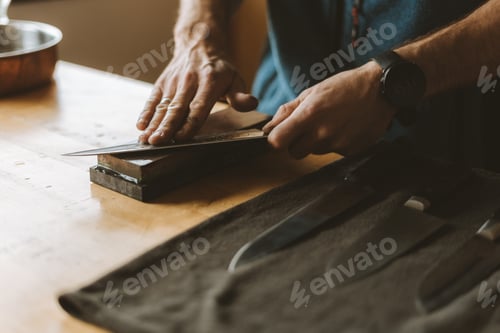 Preview: Person sharpening knives with a whetstone in the kitchen