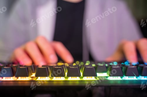 Preview: Caucasian man using the keyboard of his gamer computer with LED lights and playing games