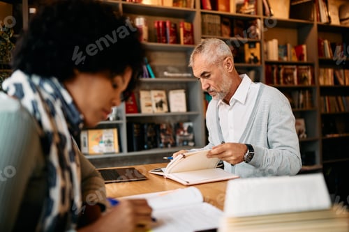Preview: Mature male student learning at university library.