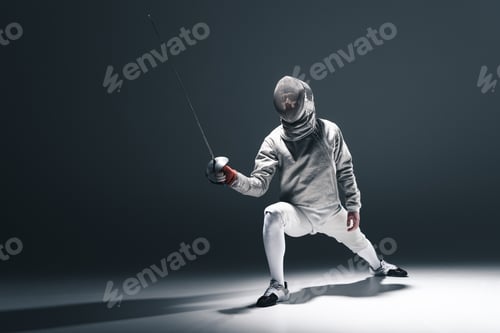 Preview: Professional fencer in fencing mask with rapier standing in position isolated on grey