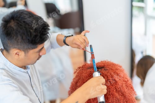 Preview: Professional hairdresser curling the hair of a woman