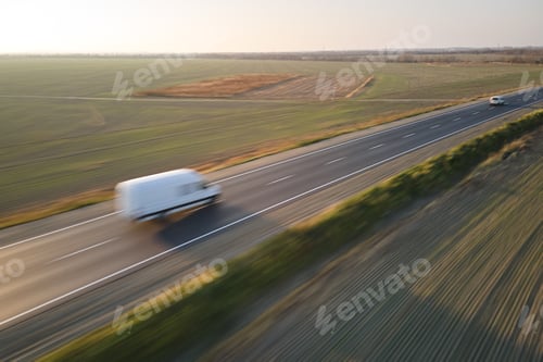 Preview: Aerial view of blurred fast moving cargo van driving on highway hauling goods. Delivery