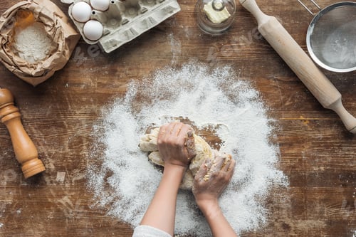Preview: top view of female hands making dough on wooden table