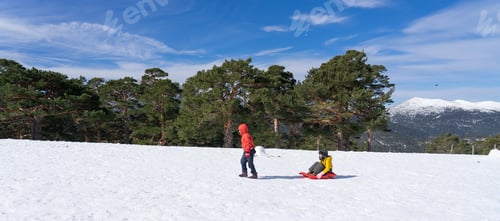 Preview: Landscape of snowy mountains and two children playing with a sled