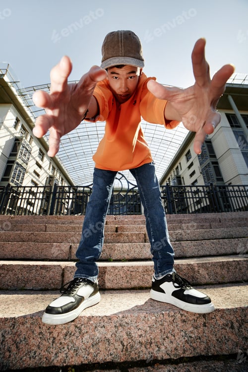 Preview: Teenage Boy Playfully Reaching towards Camera Standing on Steps Outside