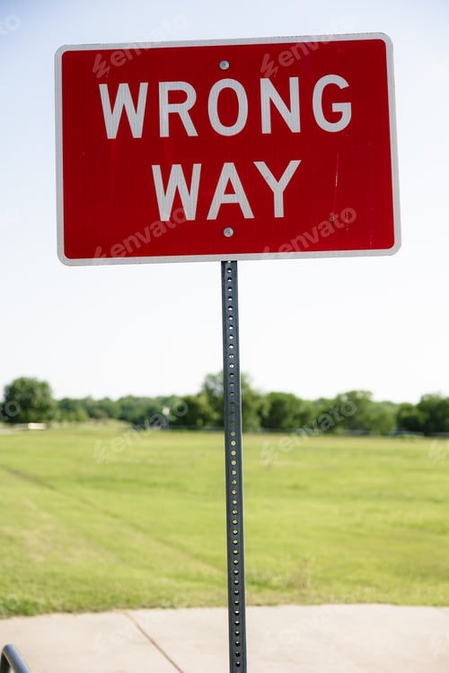 Preview: Wrong way sign on a street post in a grassy field
