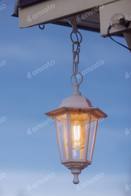 Preview: Hanging retro street lantern against a blue sky background.