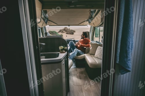 Preview: Adult man sitting inside van camper motorhome. Tourist of alternaive people lifestyle. Travel