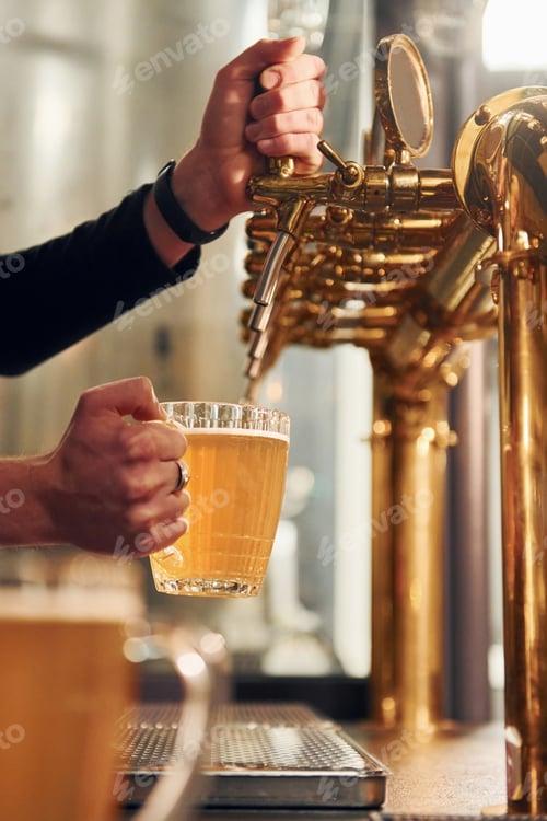 Preview: Side view of man's hands that fills glasses by beer