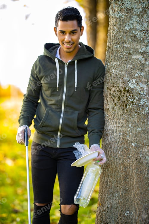 Preview: Smiling environmental protection volunteer holding garbage and mechanical grabber