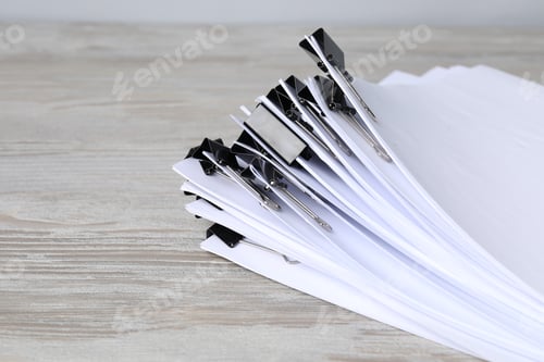 Preview: Binder clips with sheets of paper on wooden table, closeup. Space for text