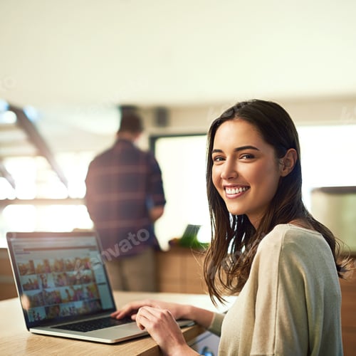 Vista previa: Retrato de una mujer joven trabajando en el ordenador portátil con su novio al fondo en casa