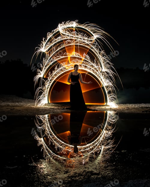 Preview: Woman posing for light painting with bright lights in the dark. Reflection in the water
