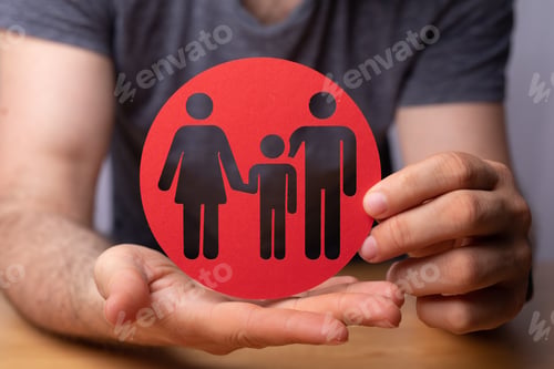 Preview: Closeup of a person holding a round red sign with family figures - family insurance concept