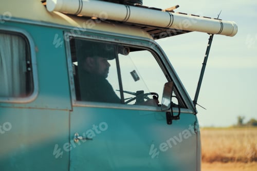 Preview: Side view of a young caucasian driver of a blue vintage van